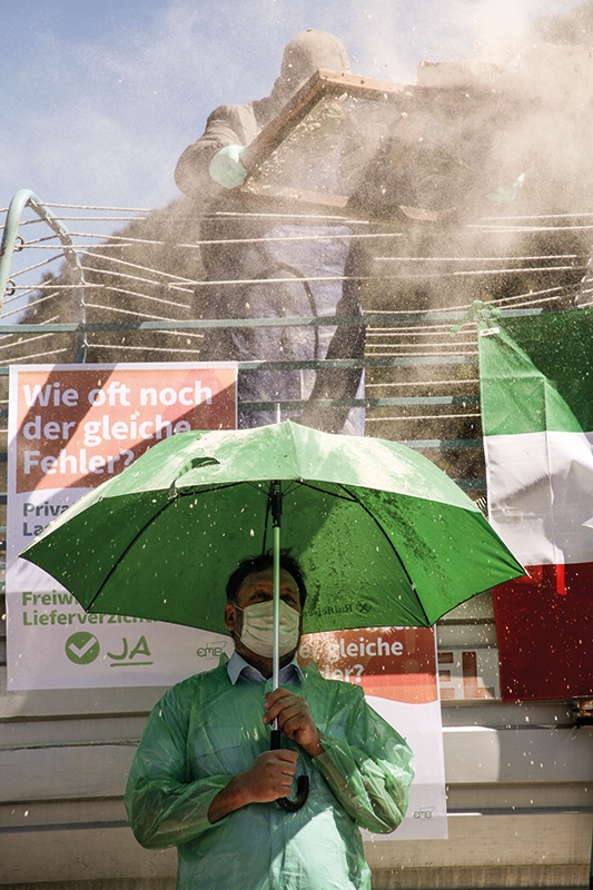 Milchpulver rieselt auf den Regenschirm von Markus Hafner: Weil die Protestaktion in Cremona verboten wurde, war der Protest in Mals stellvertretend für die italienischen Bauern in der Vereinigung European Milk Board (EMB)