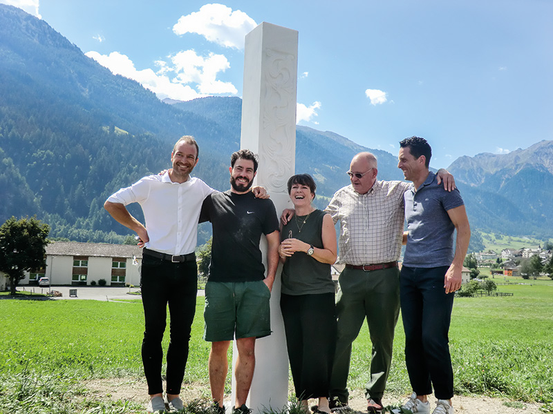 v. l.: Kurt Ratschiller, Produkt- und Marketingmanager der LASA Marmo GmbH; Elias Wallnöfer, Bildhauer; Claudia Schmauder, Szenografie Schmauder, Zürich; Walter Anderau, Präsident Stiftung Pro Kloster St. Johann Müstair, Ulrich Veith, Geschäftsführer Stiftung Pro Kloster St. Johann Müstair und dem gegenüberliegenden Hotel Chasa Chalavaina.