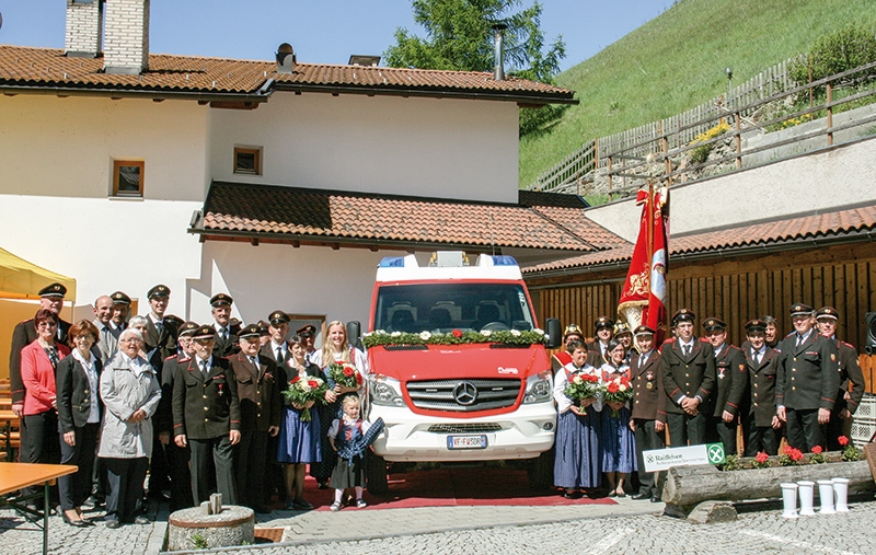 Das Kleinlöschfahrzeug flankiert von Feuerwehrleuten und Patinnen nach der Segnung