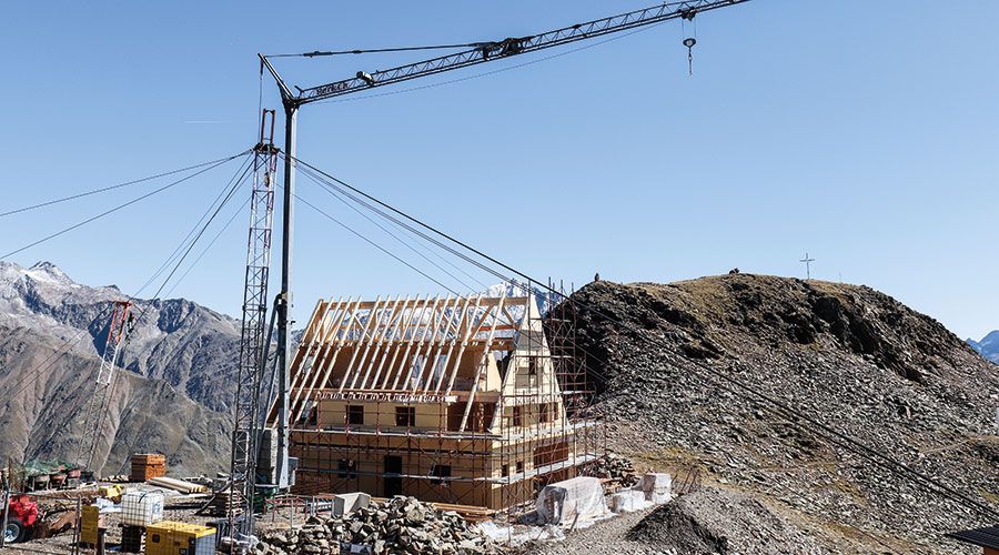 Die Wände der Heilbronner Hütte stehen, dahinter das Gipflekreuz