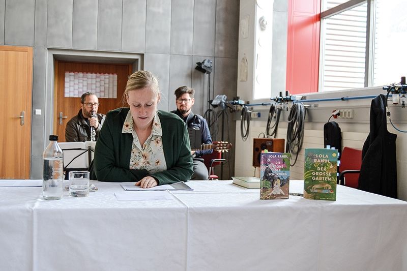 Nadia Schwienbacher las einige der Kurzkapitel, im Hintergrund die Musiker Hannes Ortler und Heiner Stecher