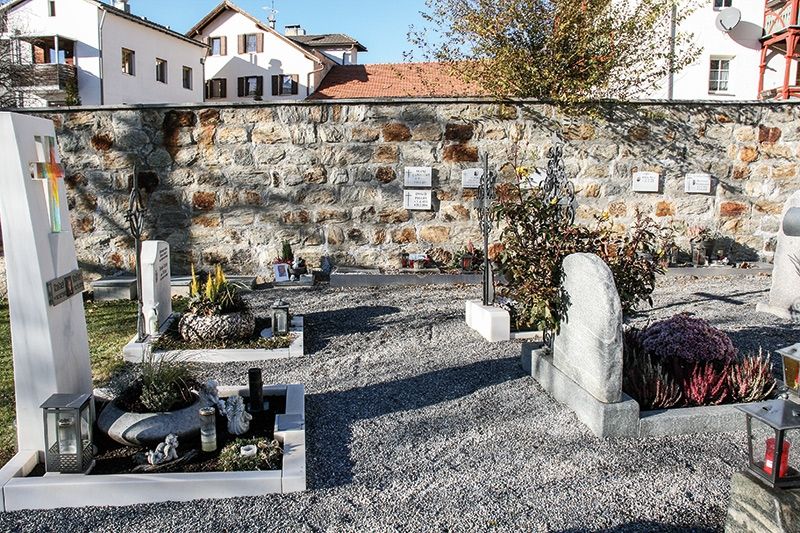 Grabreihen im neuen Teil des Schludernser Friedhofs;  im Hintergrund die Urnenschächte mit dazugehörenden Schrifttafeln an der Mauer