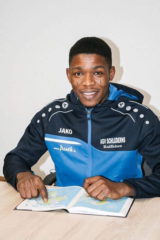 Adekunle Adewuyi, geboren 1989, stammt aus Nigeria und lebt mit seiner Frau und den zwei Kindern in Schluderns. Er wartet auf den Asylbescheid. Gerne spielt er Fußball in der Altherrenmannschaft des ASV Schluderns. Die Zeichen auf seinen Wangen stammen von einem Familien-Ritual, an das er sich nicht erinnern kann, weil er zu klein war.