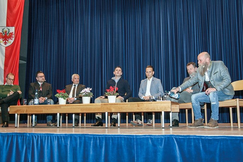 Am Podium v.l.: Franz Ploner (Landtagsabgeordneter Team K), Andreas Leiter Reber (LA Freiheitliche), Sepp Noggler (Landtagspräsident SVP), der Moderator Thomas Sinha, Sven Knoll (LA Süd-Tiroler Freiheit), Hanspeter Staffler (LA Grüne) und Jürgen Wirth Anderlan (Landeskommandant des Südtiroler Schützenbundes)