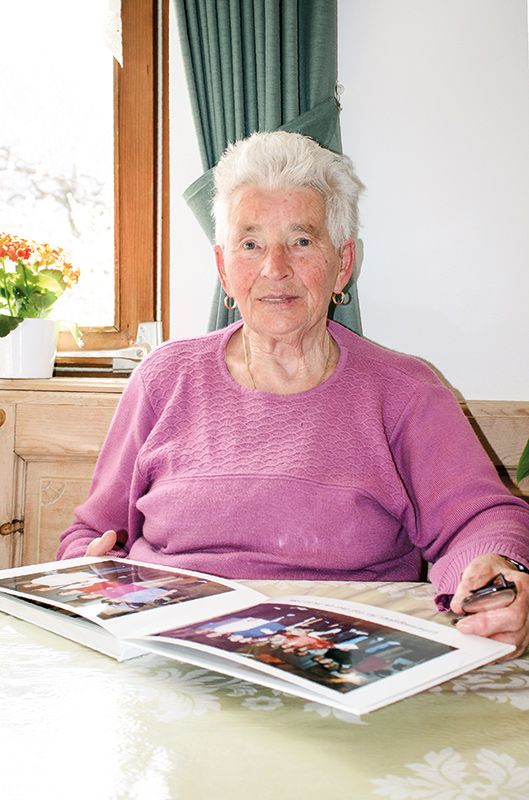 Berta Trafoier Eberhöfer, geb. 1937, Tartsch, blättert gerne im Album, das ihr die Mitglieder des Kirchenchores zum 80. Geburtstag geschenkt haben. Seit 2019 ist sie Witwe. Sie kümmert sich um ihren Haushalt, liest viel und freut sich über Besuche.