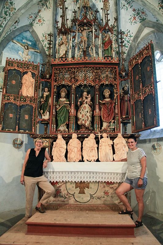 Die Vermögensverwalterin Isabella Erhard und die Restauratorin Helena Ebner vor dem Flügelaltar der Cäsariuskirche in Laatsch. Auf dem Altar 5 Nachbildungen und oben links die Nachbildung des hl. Paulus