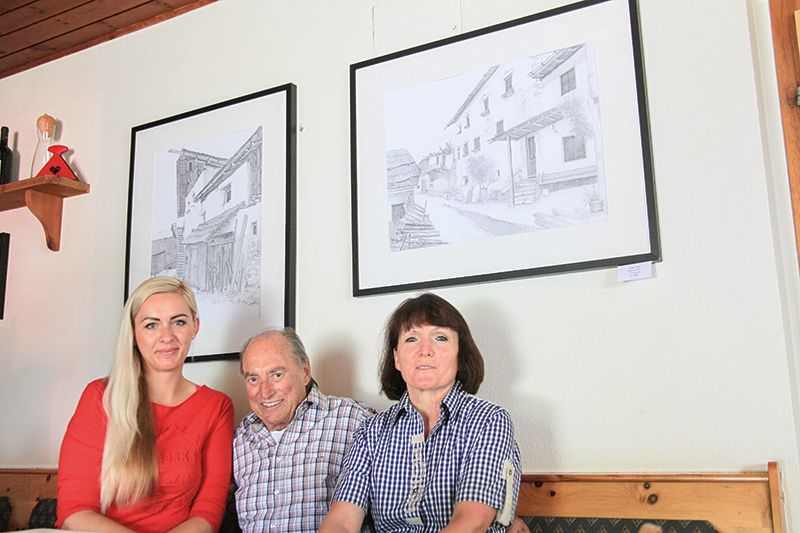 Veronika Hulmanova, Duri Fasser und Helene Wellenzohn in der Gaststube des Gasthauses Paflur oberhalb von Tanas; an der Wand zwei Zeichnungen von Duri Fasser