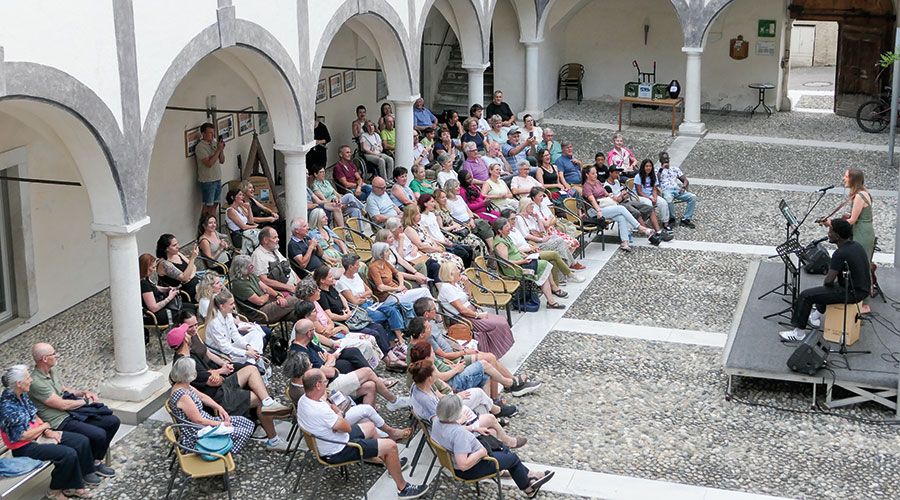und begrüßt die vielen Bersucher:innen im Innenhof der Schlandersburg zum Auftakt der Schlandersburger Sommerabende.