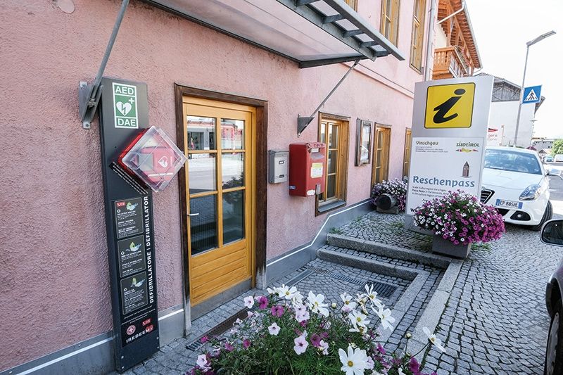 AED-Säule bei der Alten Volksschule in St.Valentin; Ein automatisierter externer Defibrillator (AED) erinnert ein wenig an einen Verbandskasten mit zwei Kabeln, an deren Enden sich jeweils ein Elektroden-Pad von der Größe einer Postkarte befindet. Diese Elektroden werden auf die Brust aufgeklebt, wenn das Herz bedrohlich aus dem Takt gerät.